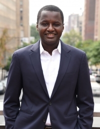 Man smiling in front of city.