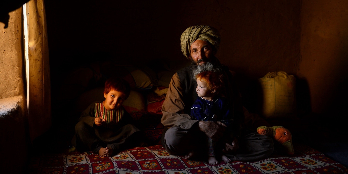 An internally displaced Afghan man sits with his children at a temporary home in a refugee camp on the outskirts of Herat, Afghanistan, on Sept. 2, 2020.