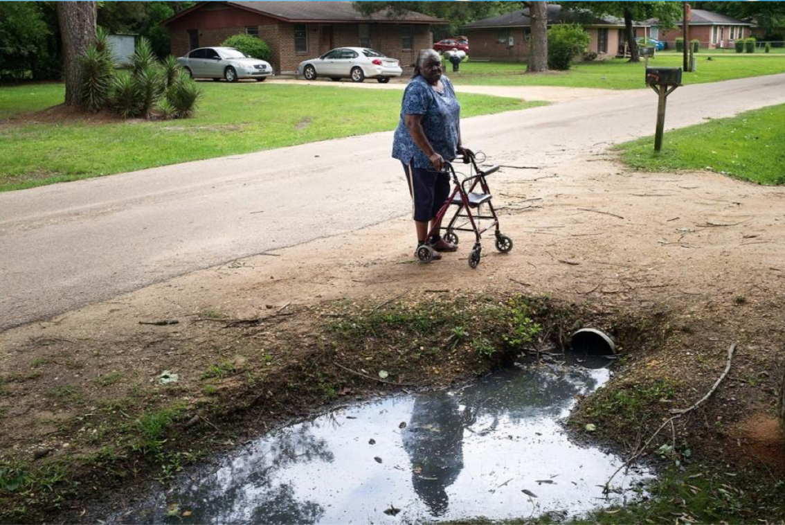 Woman standing by polluted pond.