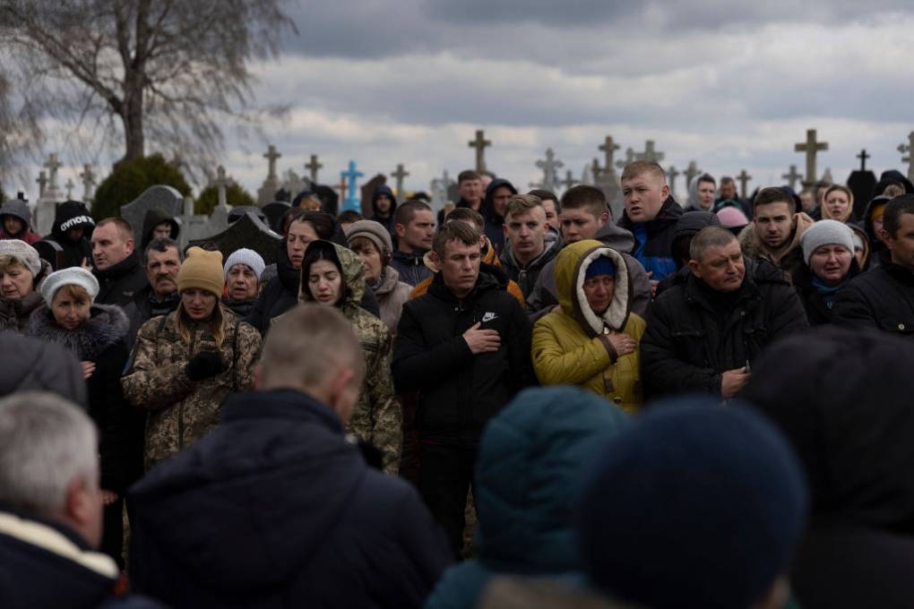 Family and friends recite the Ukrainian national anthem as they mourn Ukrainian soldier Dmitry Zhelisko during his burial on April 03, 2022 in Rusyn, Ukraine.